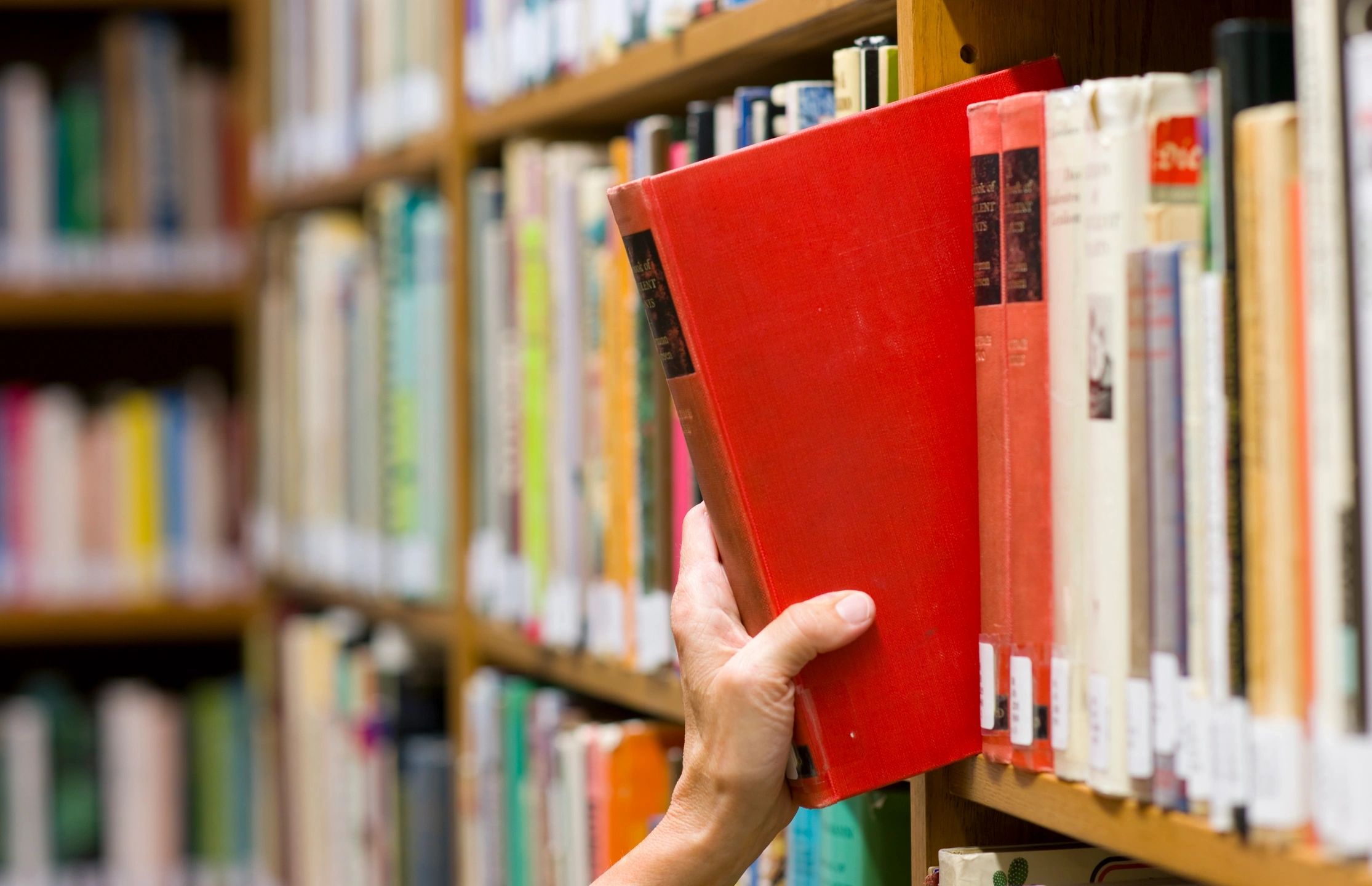 books on a bookshelf, with a hand removing one book